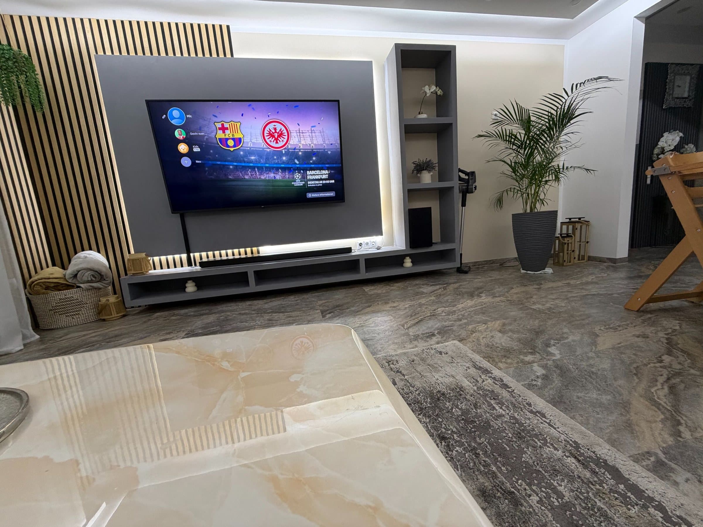 Wohnzimmer mit Marmorboden und großer Smart-TV-Wand