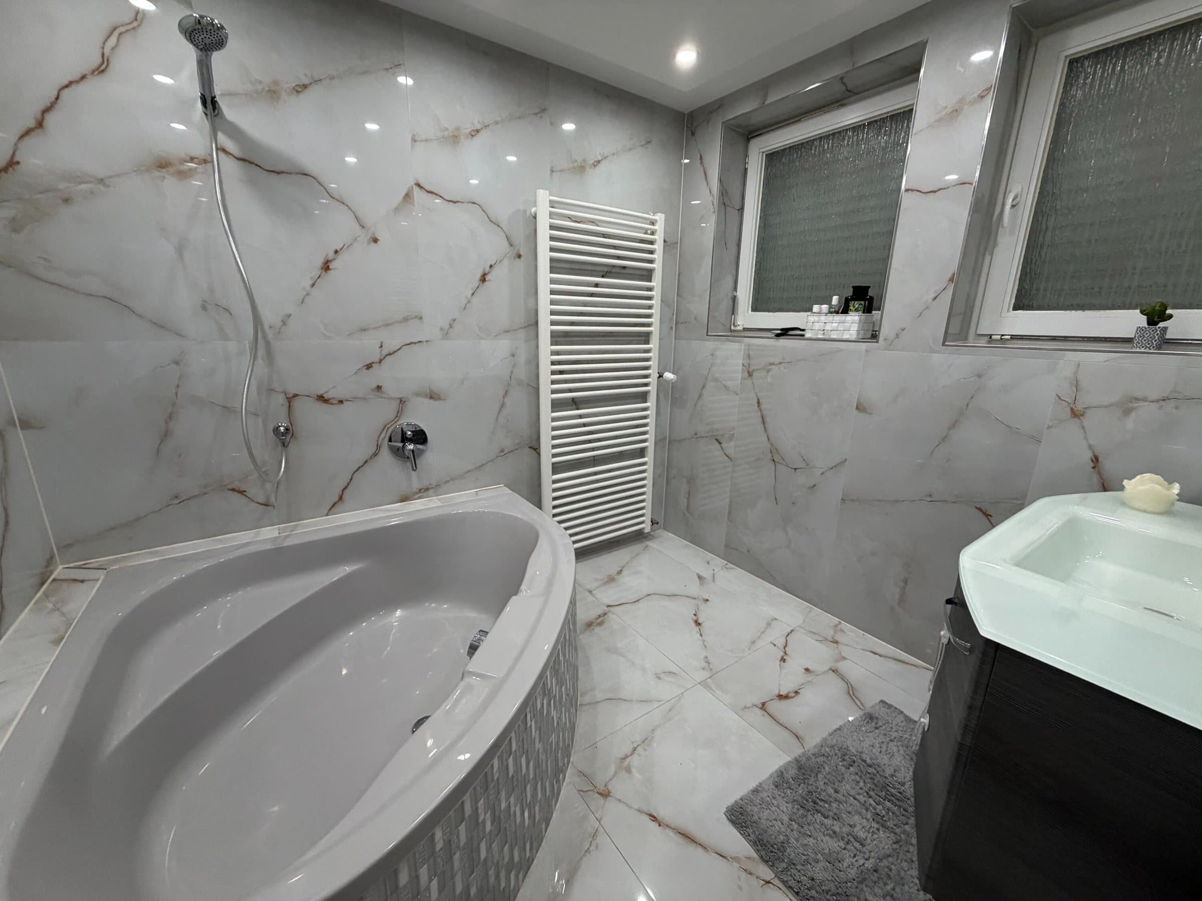 Badezimmer in Marmor-Optik mit Eckbadewanne