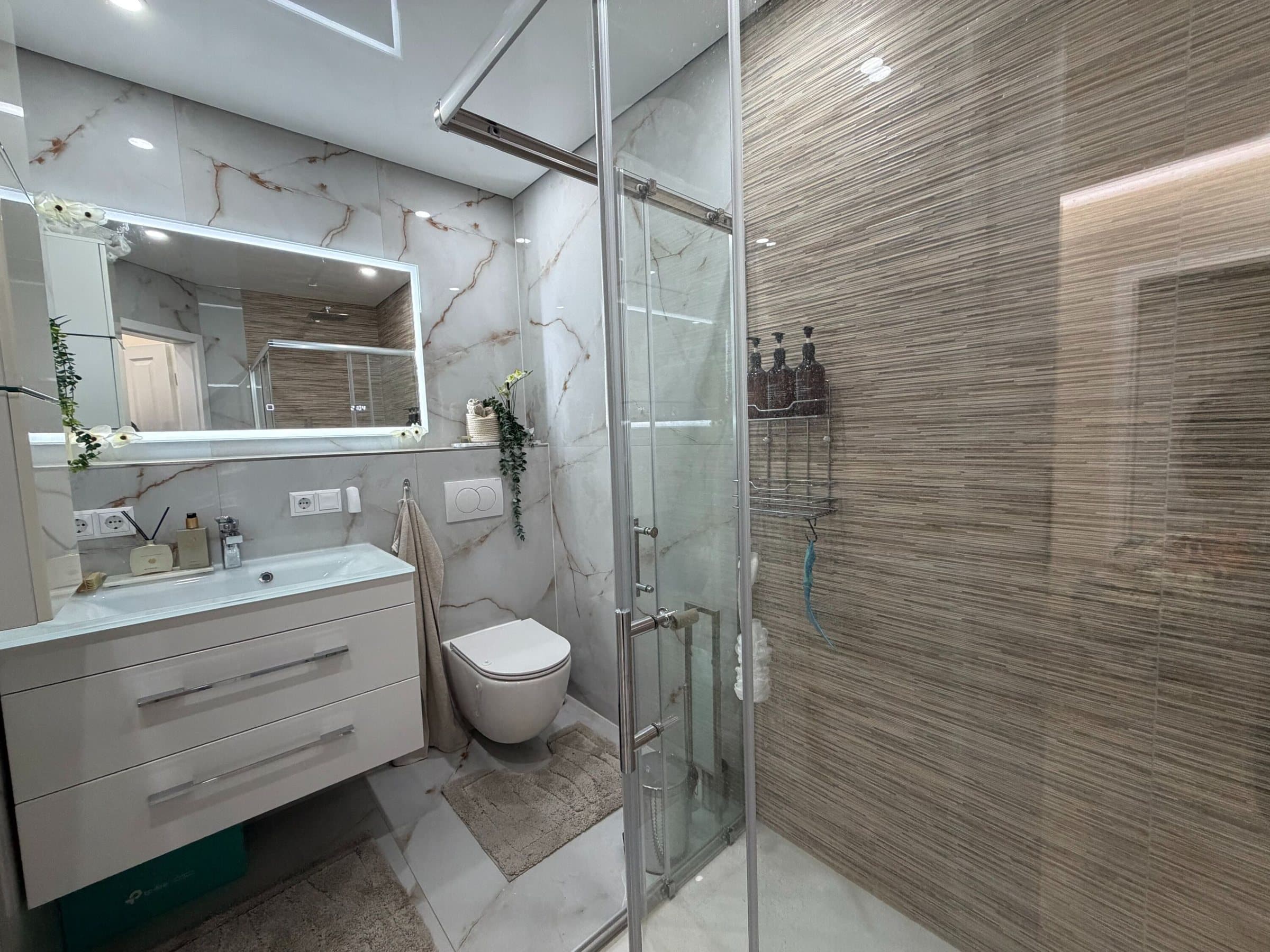 Badezimmer mit Glasdusche und Waschtisch