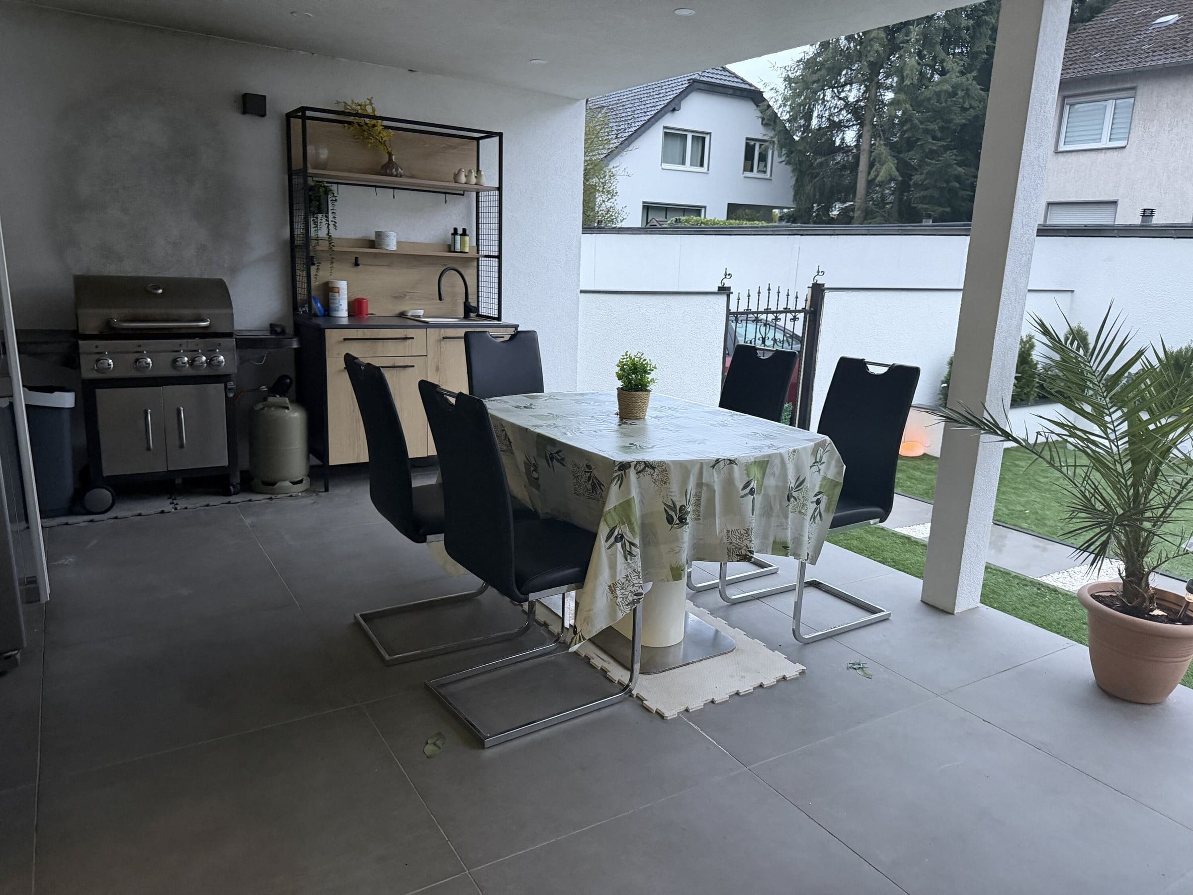 Überdachte Terrasse mit Grill und Esstisch