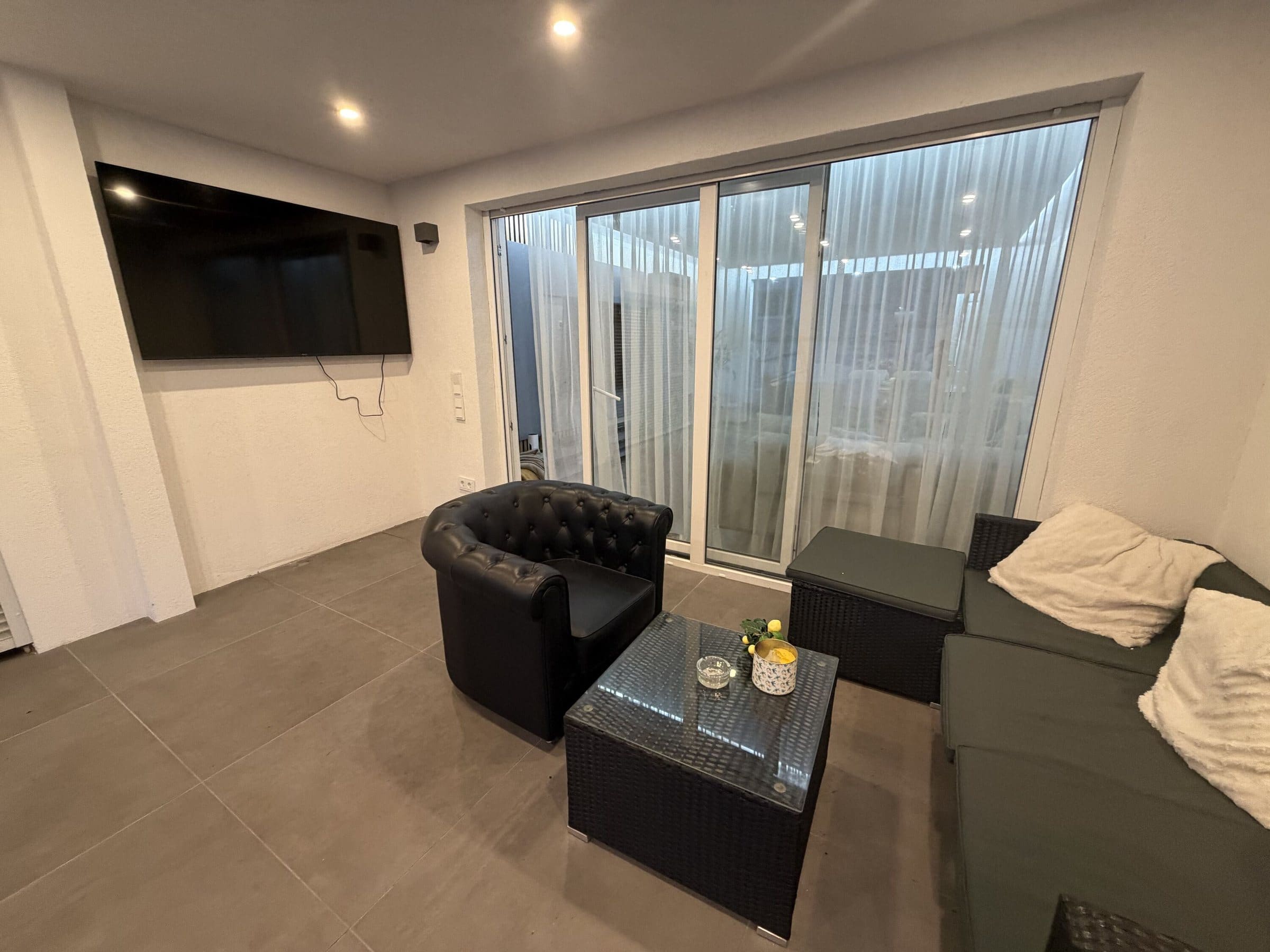 Lounge-Raum mit Sofa und TV an der Terrasse