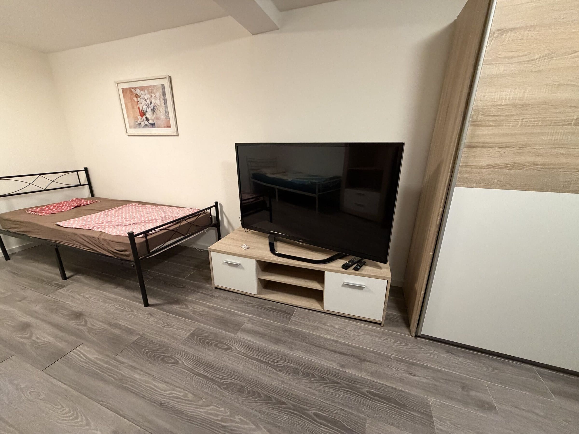 Schlafzimmer mit Bett, Schrank und Fernseher