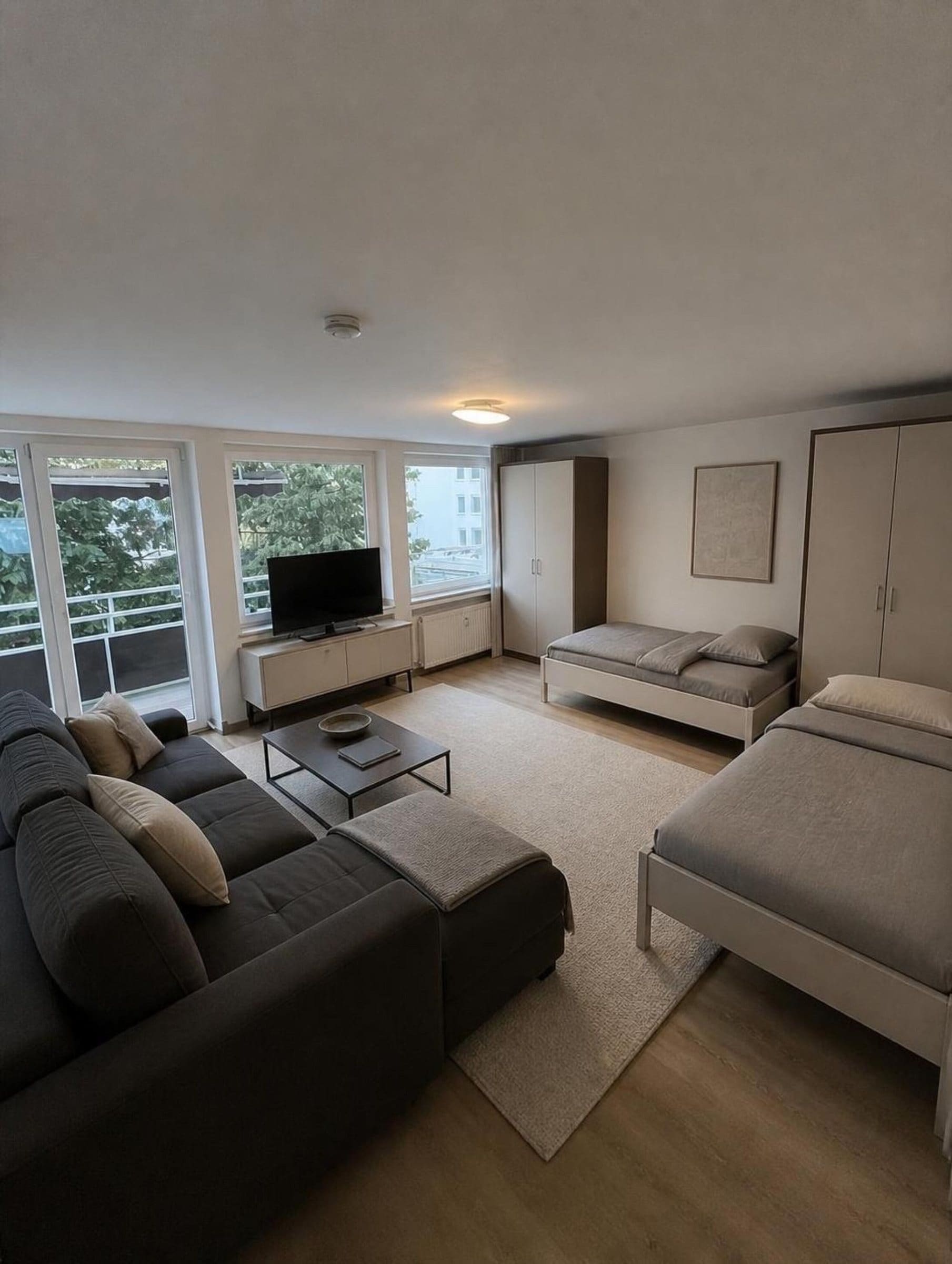 Wohnzimmer mit Sofa, Fernseher und Balkontür